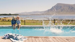A wooden deck with a pool, a blanket, and a mountain view in the background. - Coot Club (Stanford)