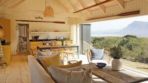 A spacious living area with a wooden ceiling, a dining table, and a view of the outdoors. - Coot Club (Stanford)