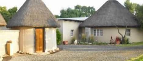 Ein traditionelles Haus mit einem Strohdach, einer kleinen Holztür und einem Schotterweg.