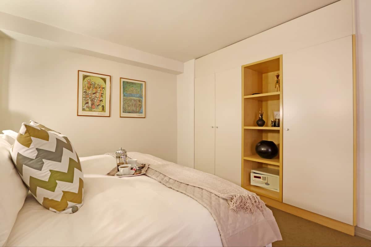 Ein Schlafzimmer mit einem Bett, einem Nachttisch, einem Regal mit Dekoration und zwei gerahmten Bildern an der Wand.