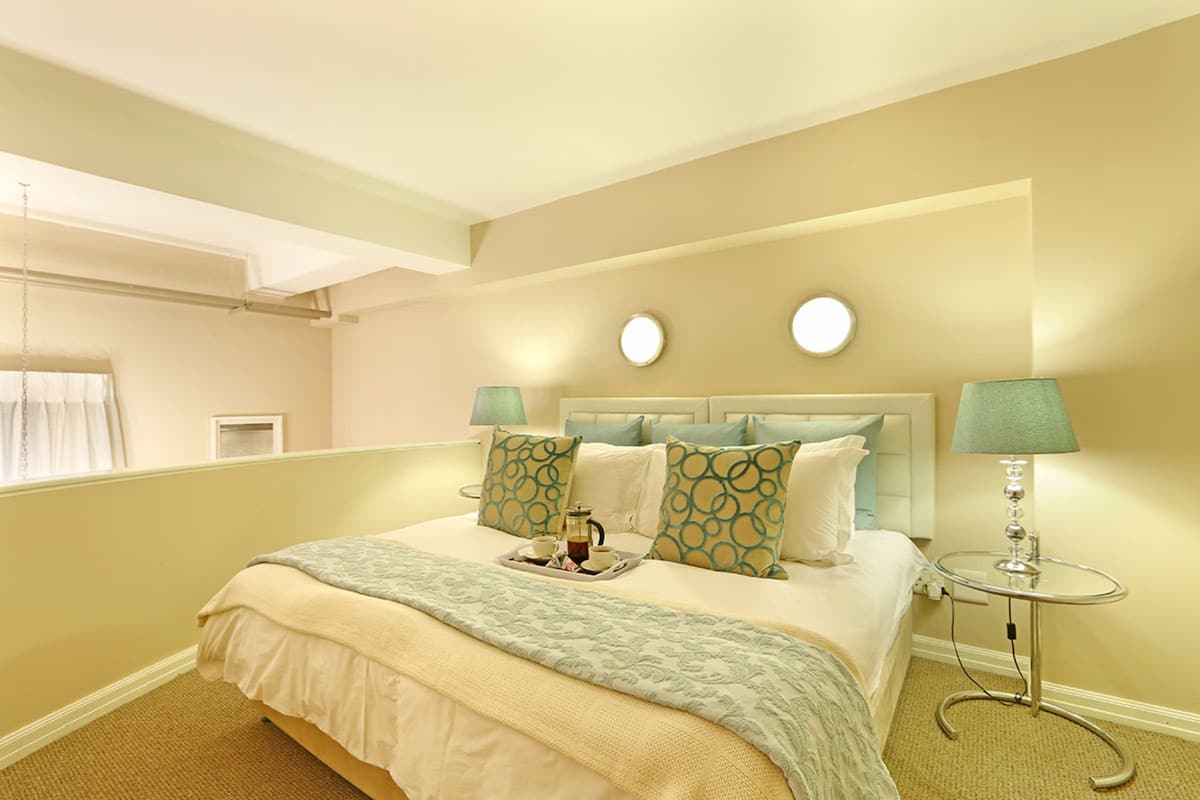 Ein Hotelzimmer mit einem Bett, zwei Nachttischlampen, einem Nachttisch und einem Fenster, an dem ein Handtuch hängt.