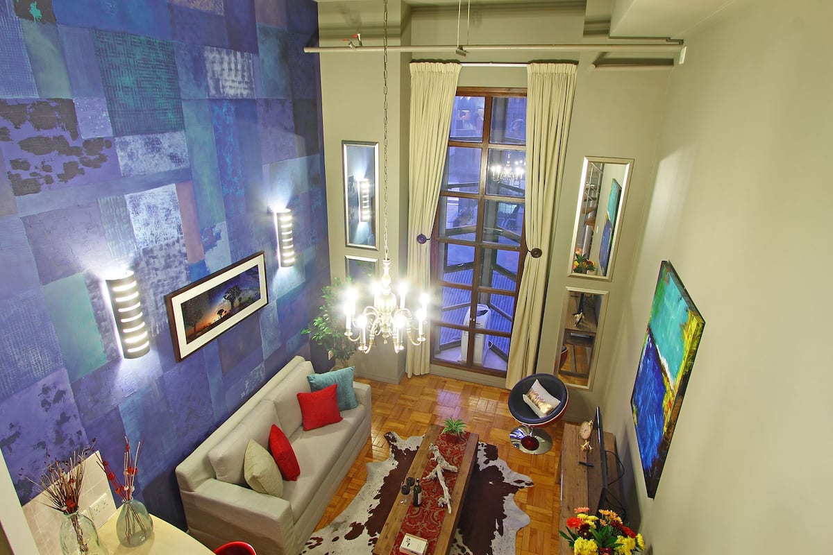 Ein Wohnzimmer mit einer Couch, einem Couchtisch, einer Kristallleuchtre und einem großen Fenster mit Vorhängen.