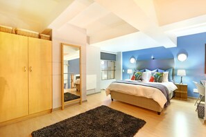 A bedroom with a bed, wooden wardrobe, mirror, and a round mirror on the wall.