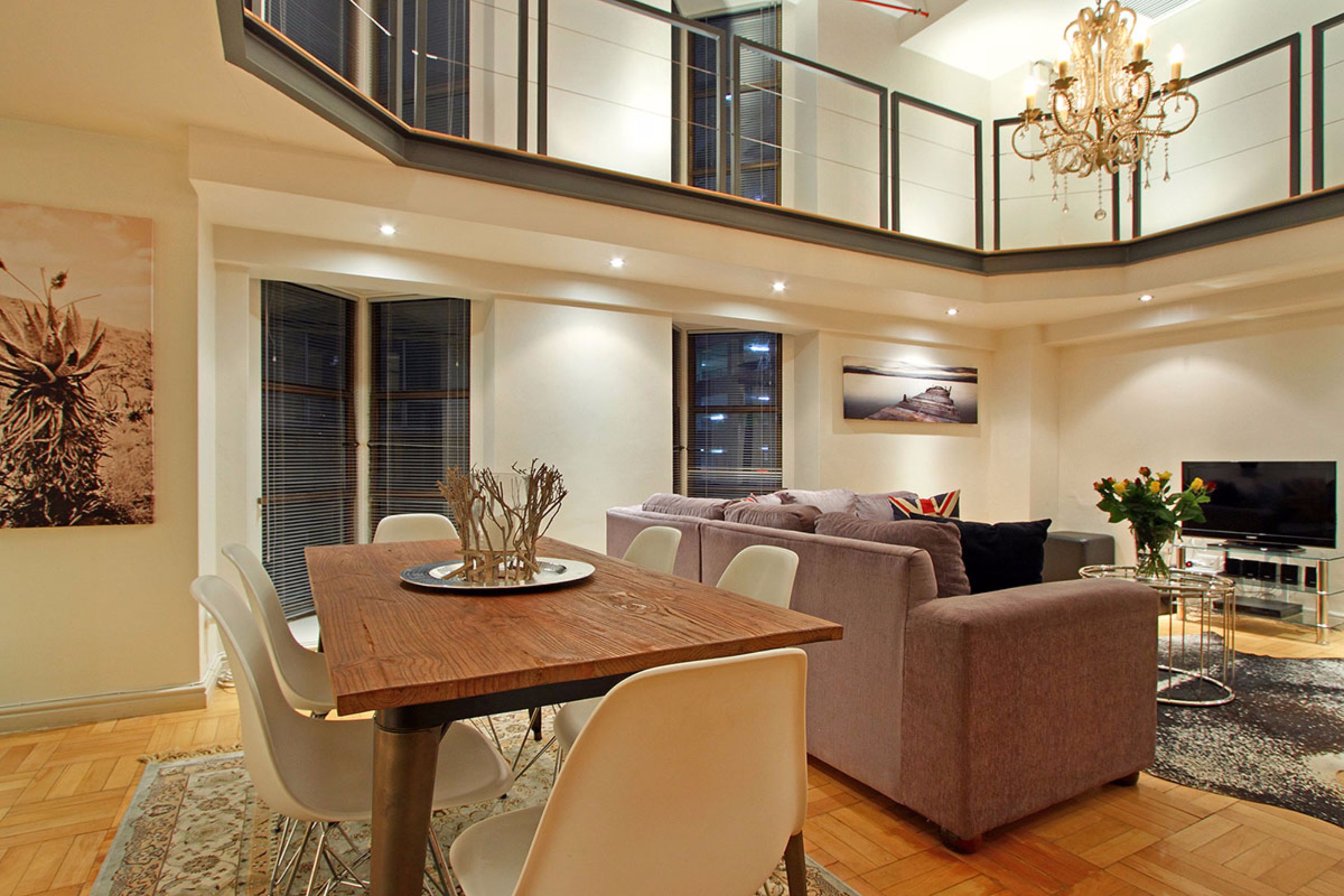 Una sala de estar moderna con comedor, sofá, televisor y candelabro.