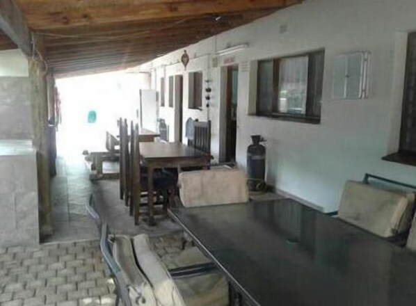 Enjoy meals under a covered outdoor dining area with a long table and comfortable seating.
