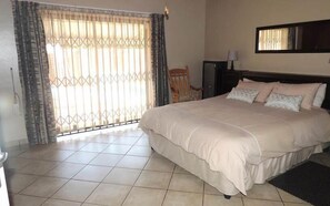 Relax in a spacious room with a large bed, a small table, and a comfortable chair.