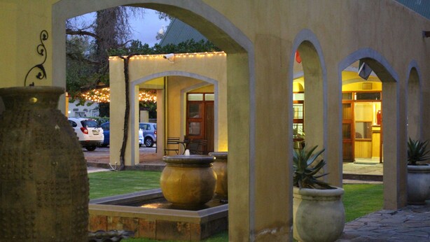 An outdoor courtyard with stone arches, a water feature, and potted plants. - 17 on Bird Guest House (Beaufort West)