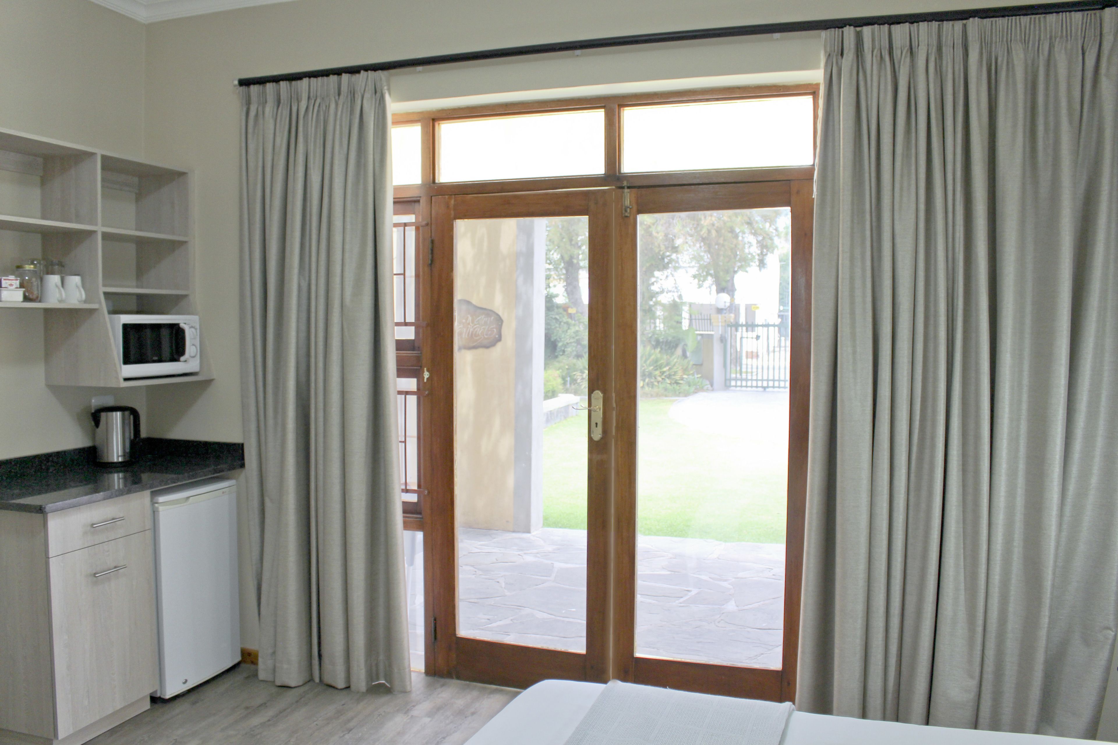 A kitchen with a microwave, coffee maker, and cabinets. There is a sliding glass door leading to a patio with a stone floor.