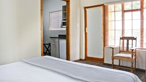 A bedroom with a bed, a wooden chair, a desk, and a window with blinds. - 17 on Bird Guest House (Beaufort West)