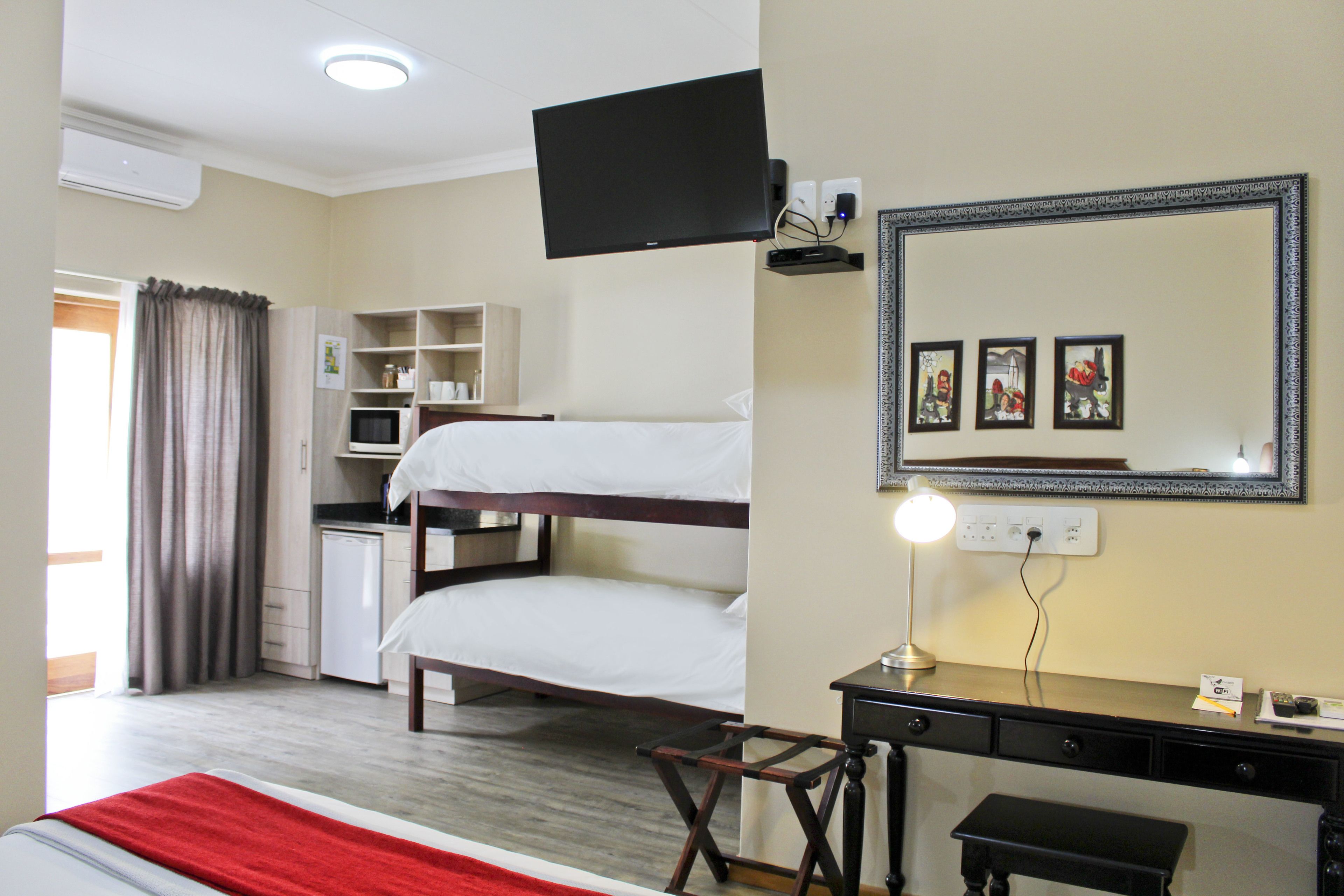 Habitación de hotel con literas, escritorio, silla y televisión instalada en la pared.