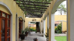 A covered outdoor area with stone flooring, potted plants, and a bicycle mounted on the wall. - 17 on Bird Guest House (Beaufort West)