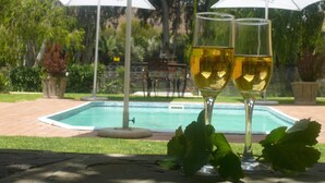 Two wine glasses with a pool and umbrellas in the background. - 17 on Bird Guest House (Beaufort West)