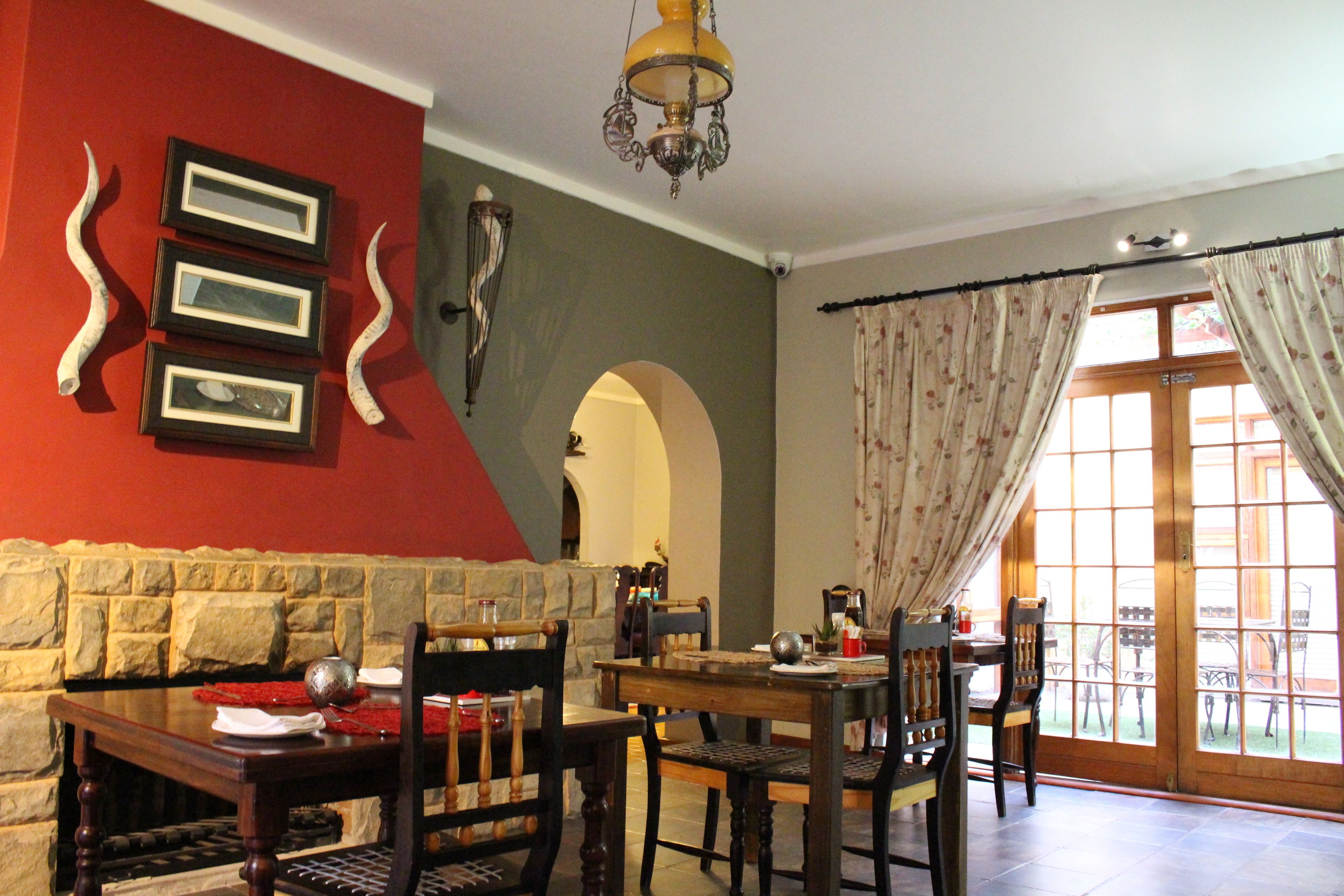 A dining area with a stone wall, wooden furniture, and a view through a glass door.