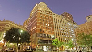 A multi-story hotel with a prominent corner location, featuring a mix of brick and modern facade, large windows, and a visible entrance. - Afribode Acc Piazza (Cape Town)