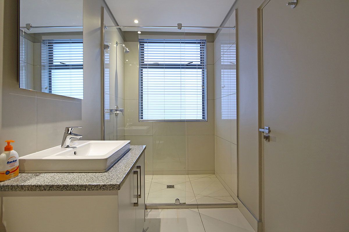 A modern bathroom with a sink, mirror, and shower.