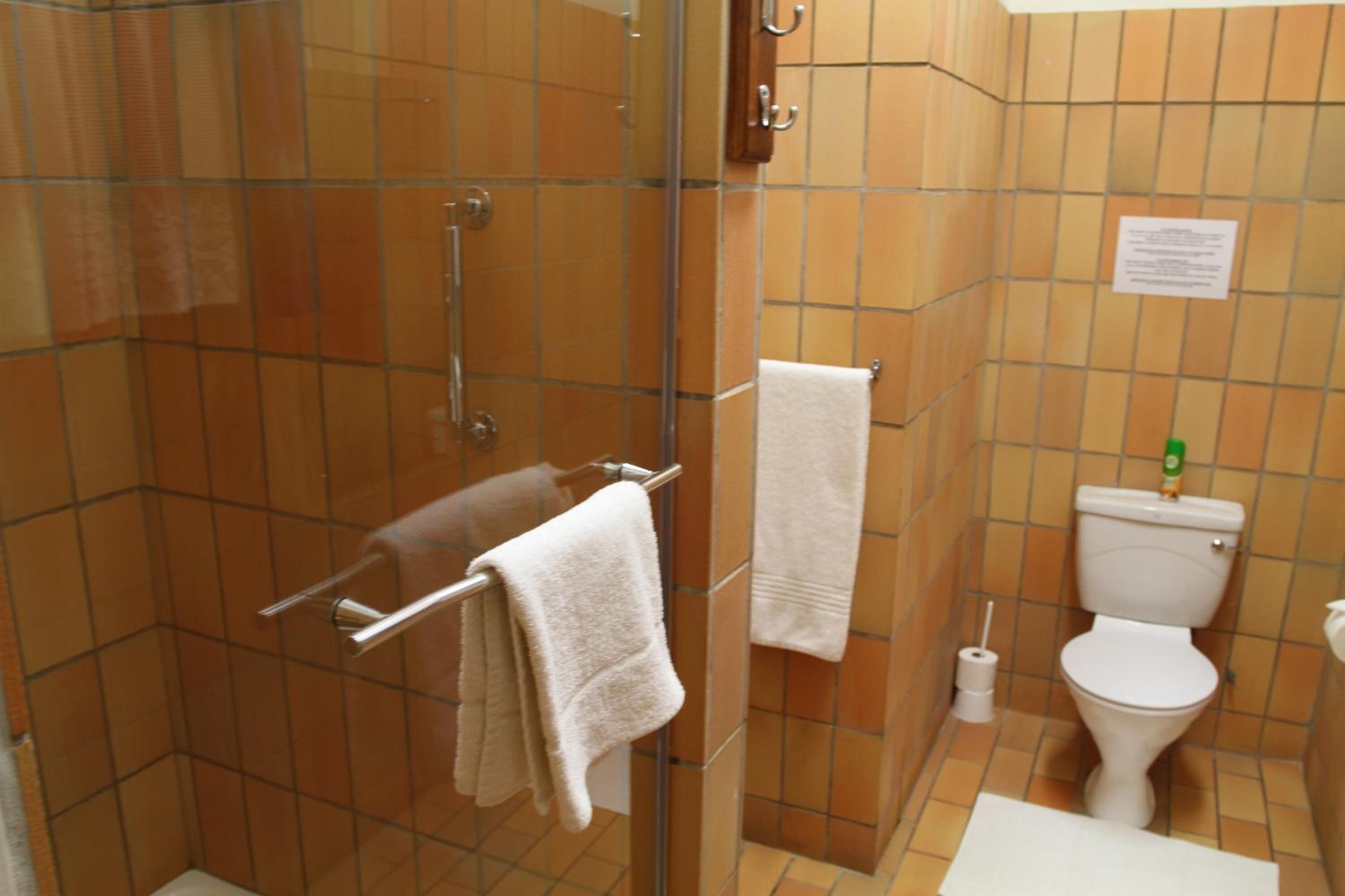 Un baño con ducha envuelta en vidrio, inodoro y lavabo.