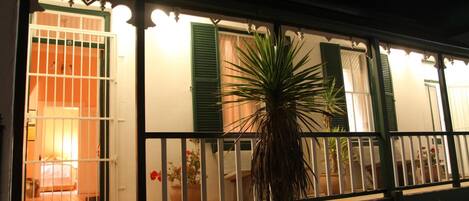 Un bâtiment doté d’un balcon, d’une porte et de plantes en pot.