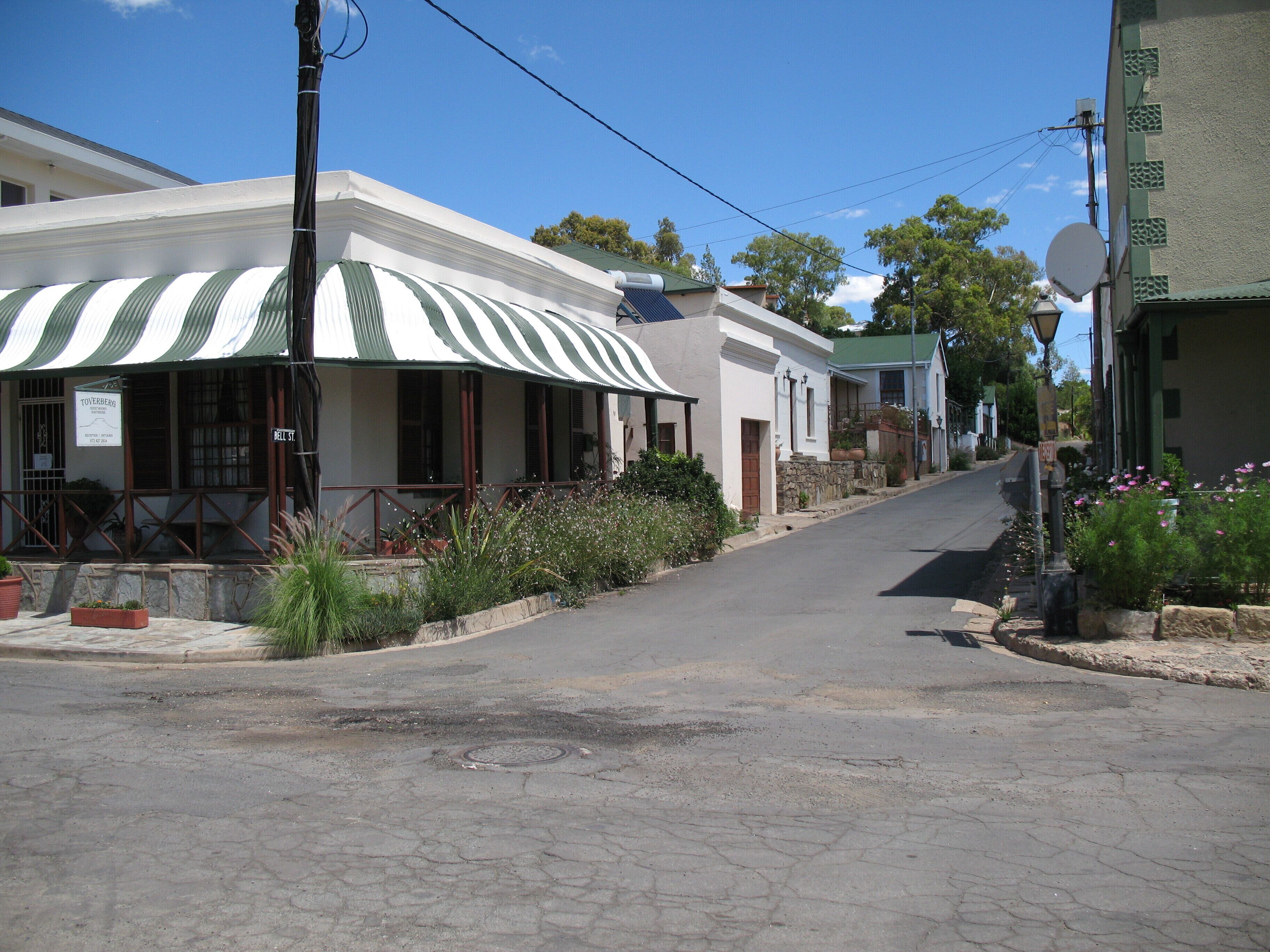 A street with buildings, including a two-story structure with a green and white striped awning.