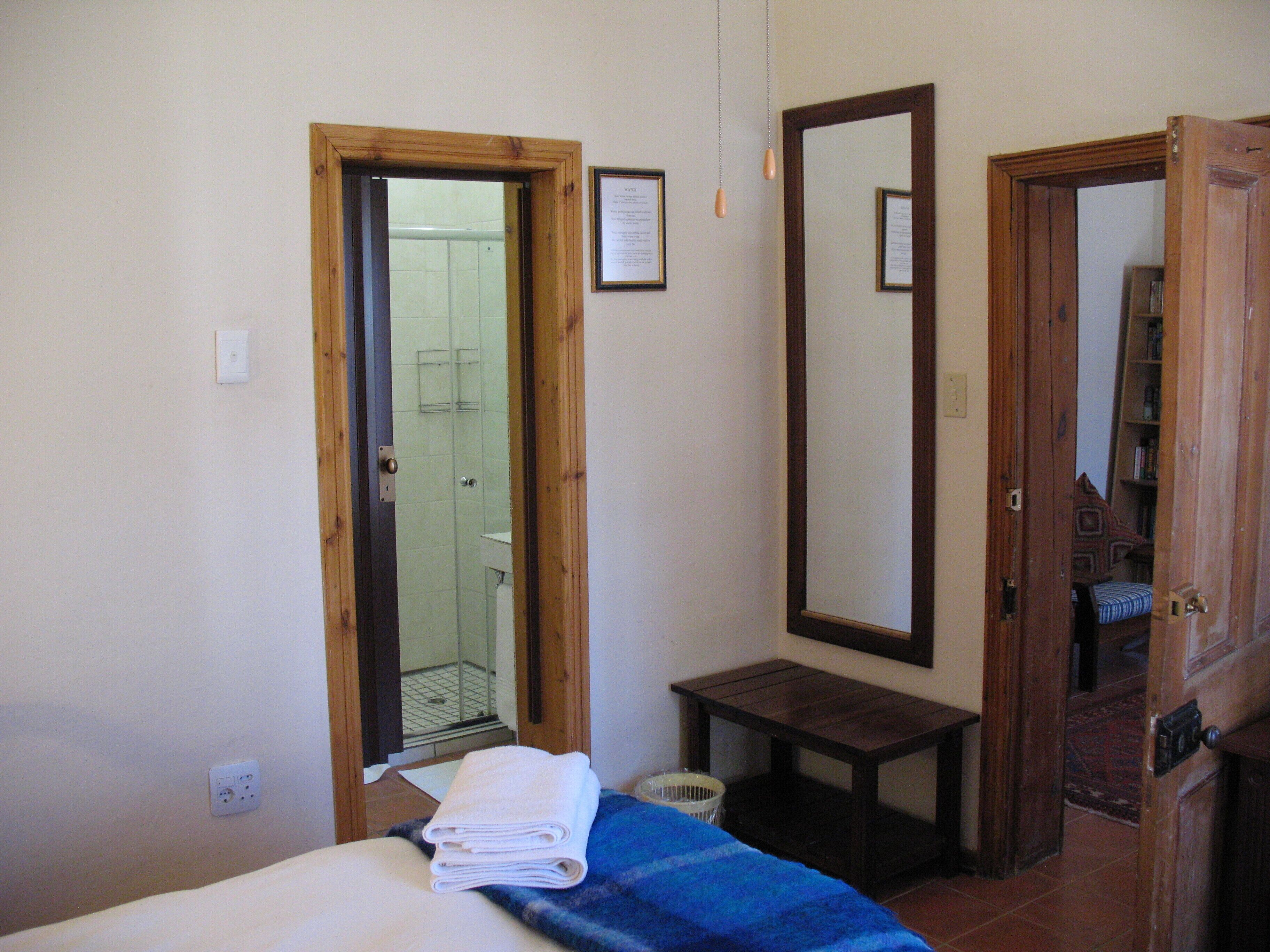 A bedroom with a bed, a small table, a mirror, and a door leading to a bathroom.