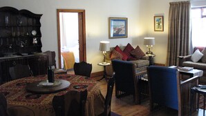 A traditional living room with a dining table, chairs, a sofa, and a bookshelf.