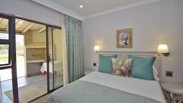 A hotel room with a large bed, two wall-mounted lamps, a painting, and a sliding glass door leading to a balcony.