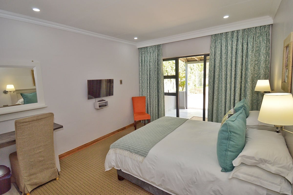 A hotel room with a bed, a chair, a desk, a television, and a view of the outdoors.