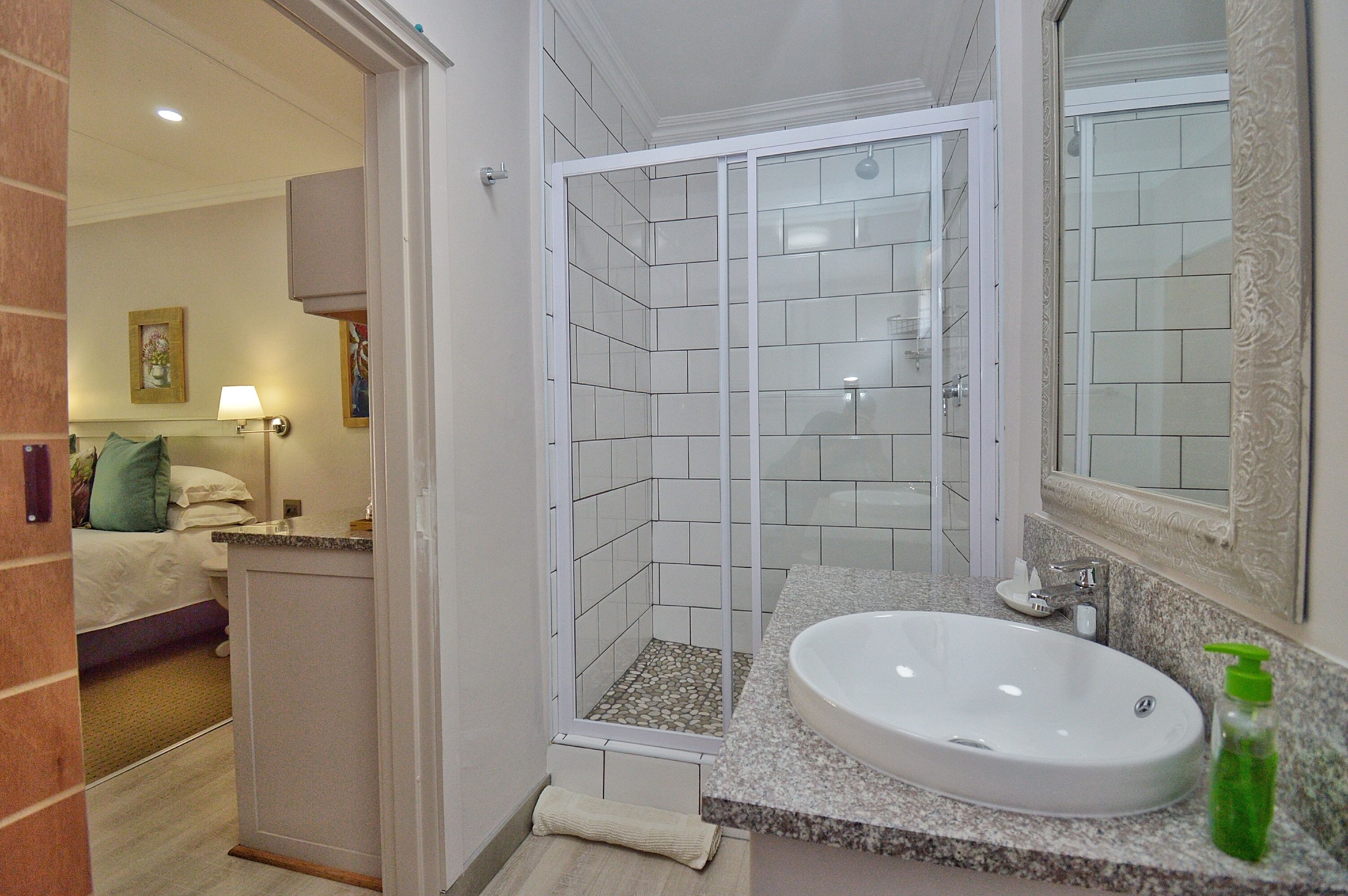 Un baño de hotel con ducha, lavabo y espejo.