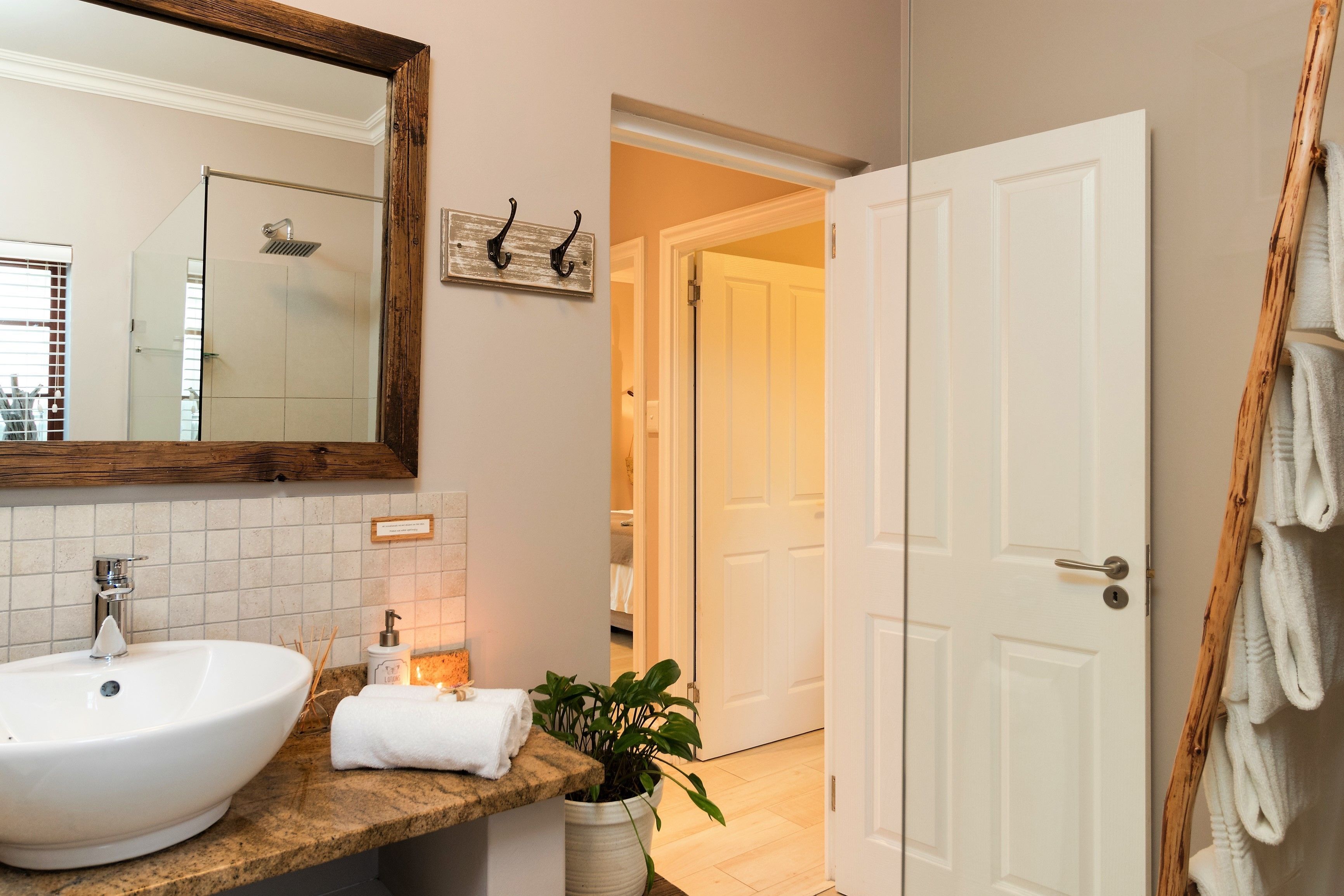A bathroom with a large mirror, a sink, a towel rack, and a door leading to another room.