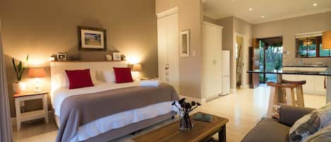 A bedroom with a bed, bedside tables, a nightstand, a wooden bench, and a bedside lamp.