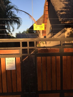 A gated entrance with a sign warning of electric fence and a contact number for assistance.