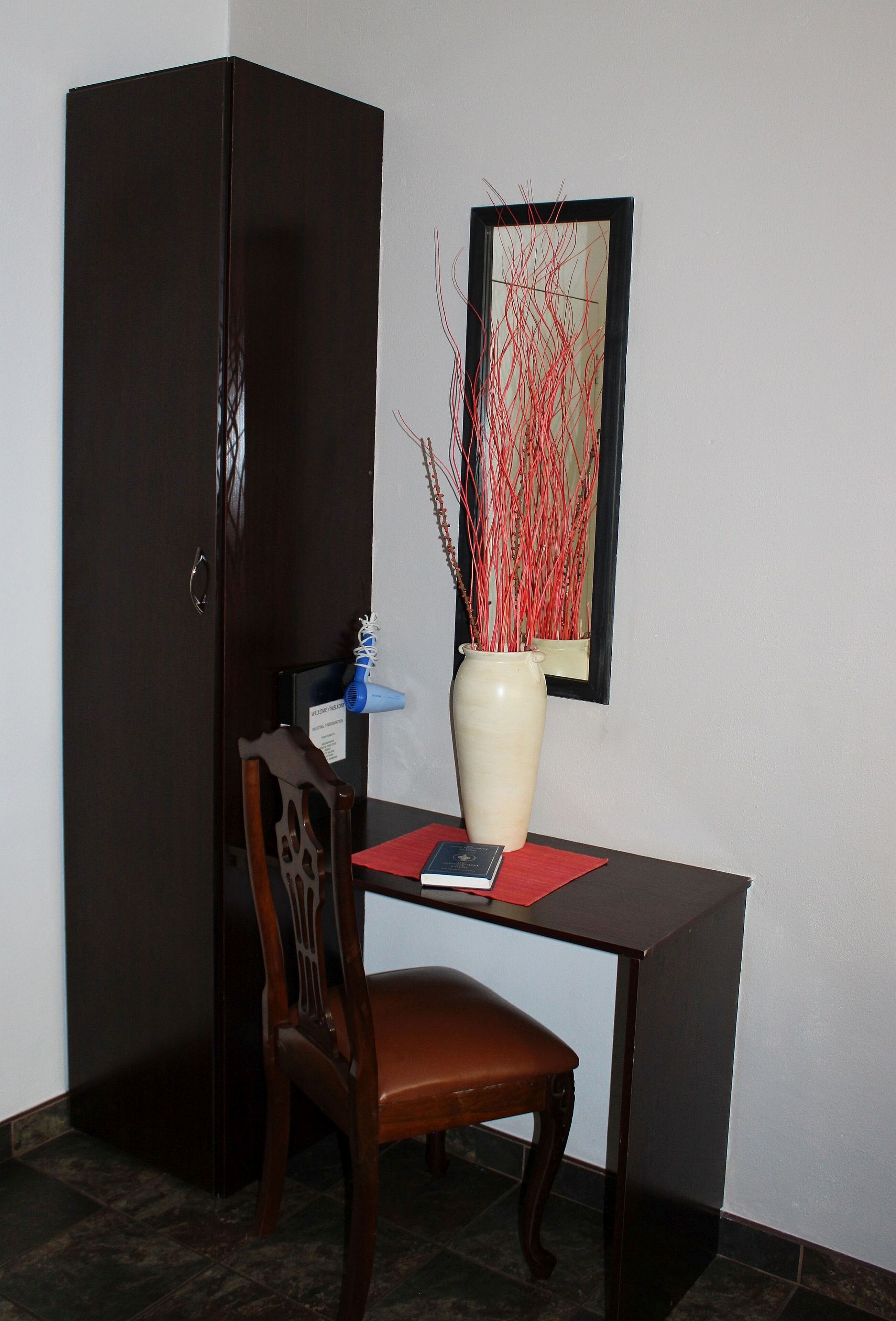 A room with a wooden cabinet, a desk with a vase, and a chair.