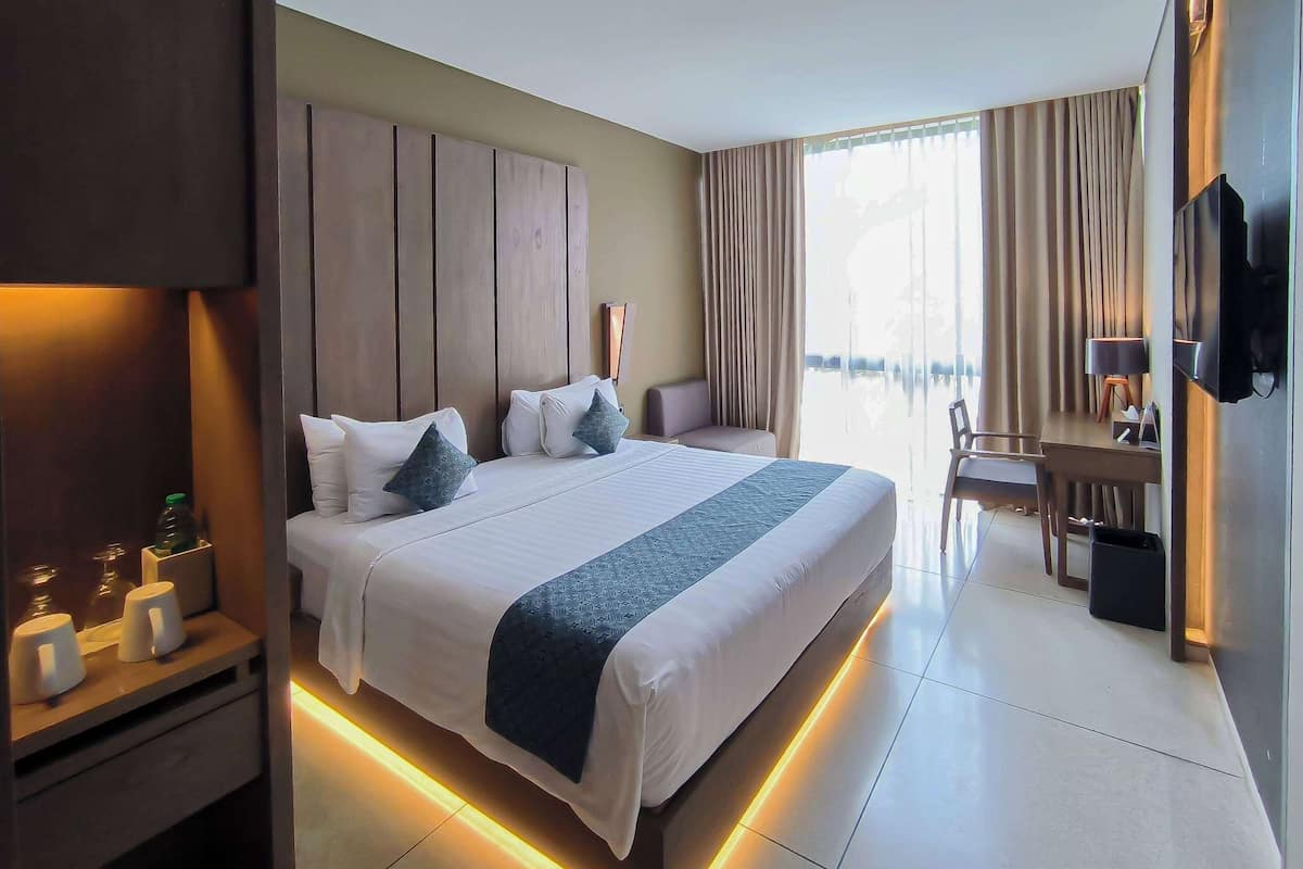 Une chambre d’hôtel moderne, dotée d’un grand lit, de tables de chevet, d’un bureau et d’une télévision.