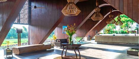 A spacious lobby with a high ceiling, wooden beams, and a central table with a vase of flowers.