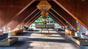Un atrio interior con techo alto, vigas de madera y un área de estar central con sofás y una mesa de centro.