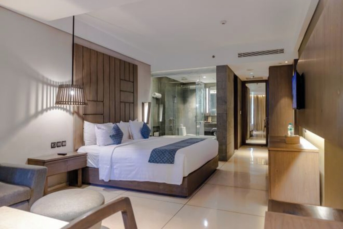 A modern hotel room with a large bed, bedside tables, a desk, and a TV mounted on the wall.