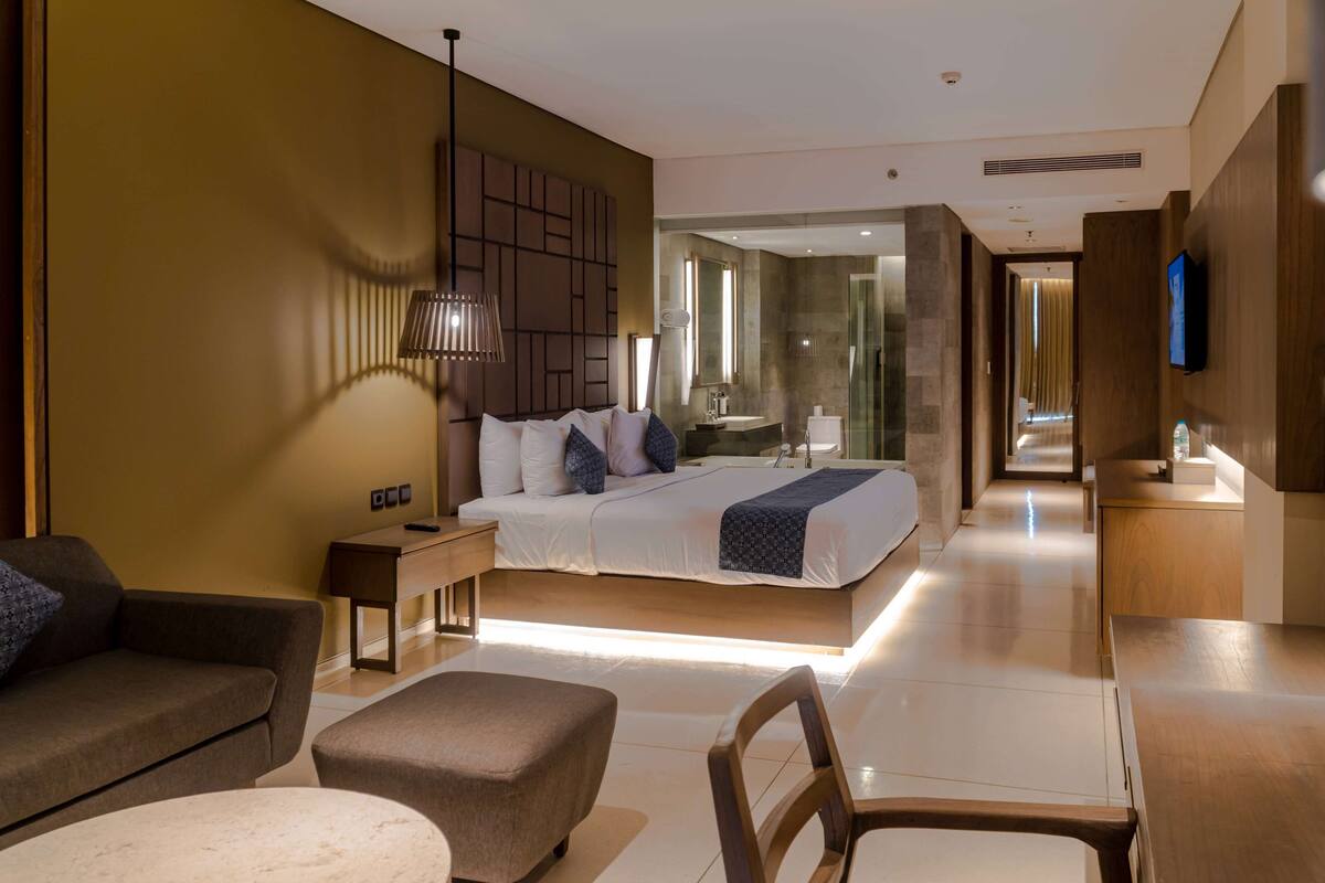 Une chambre d’hôtel moderne équipée d’un grand lit, d’un canapé, d’un bureau et d’une télévision.