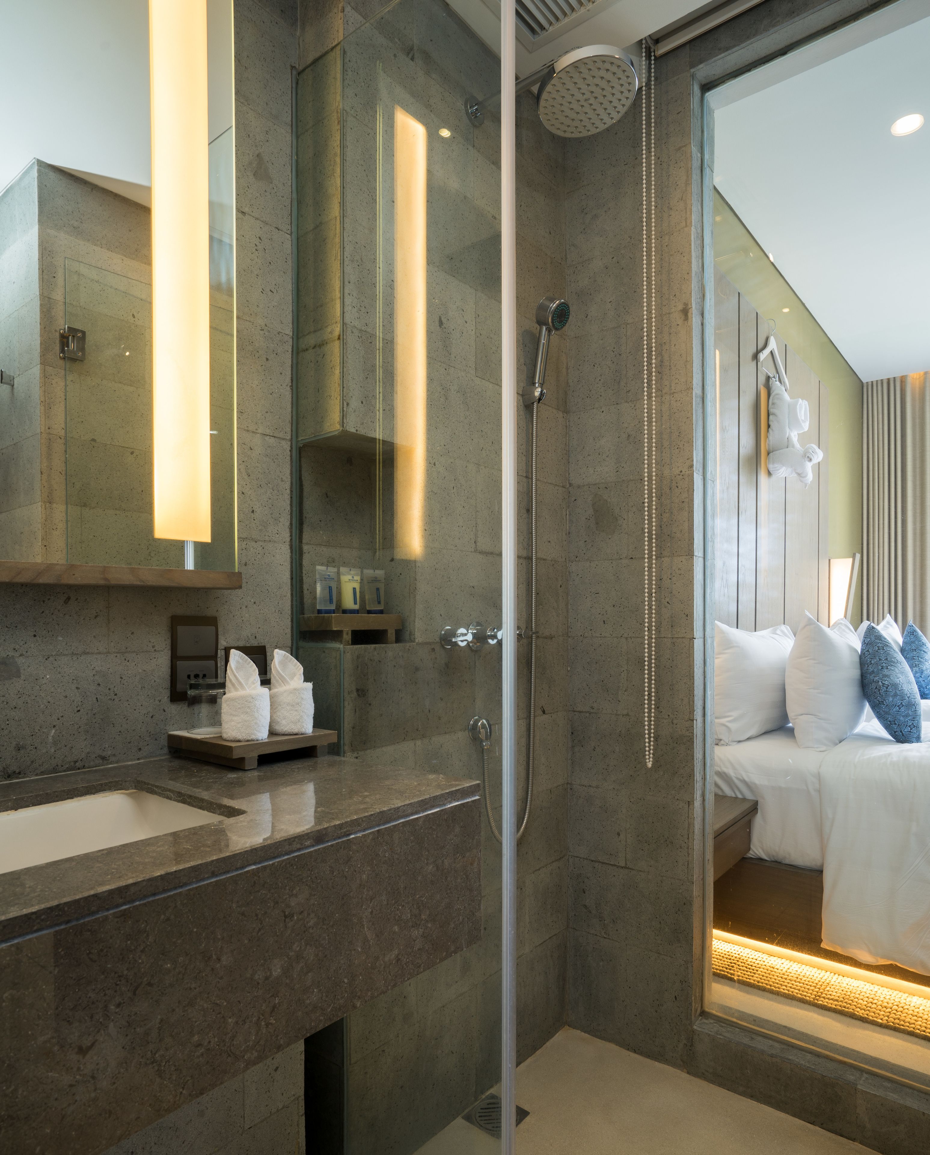 Un baño moderno con cabina de ducha de vidrio, un espejo grande y un tocador con lavamanos y calentador de toallas.