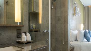A modern bathroom with a glass shower enclosure, a large mirror, and a vanity with a sink and towel warmer.