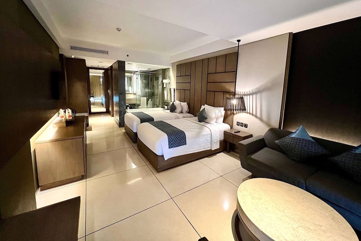 Une chambre d’hôtel moderne avec un grand lit, un canapé, une table de chevet et un miroir.