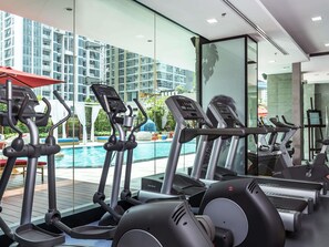 A gym with treadmills, ellipticals, and a pool view. - Mercure Bangkok Sukhumvit 11 (Bangkok)