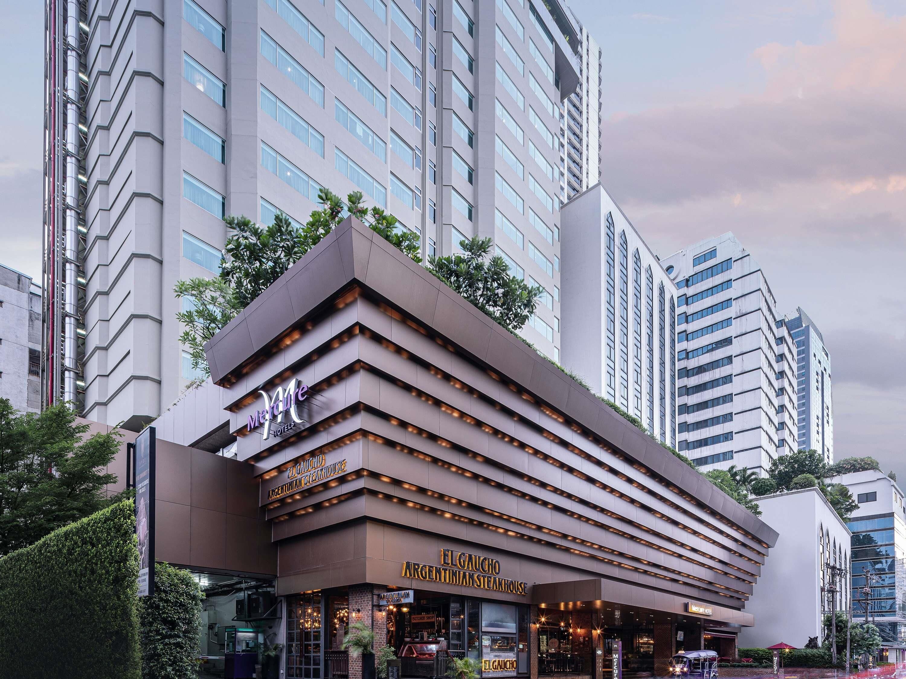 A modern hotel with a prominent entrance, a visible restaurant named 'El Gaucho Argentinian Steakhouse,' and a large building in the background.