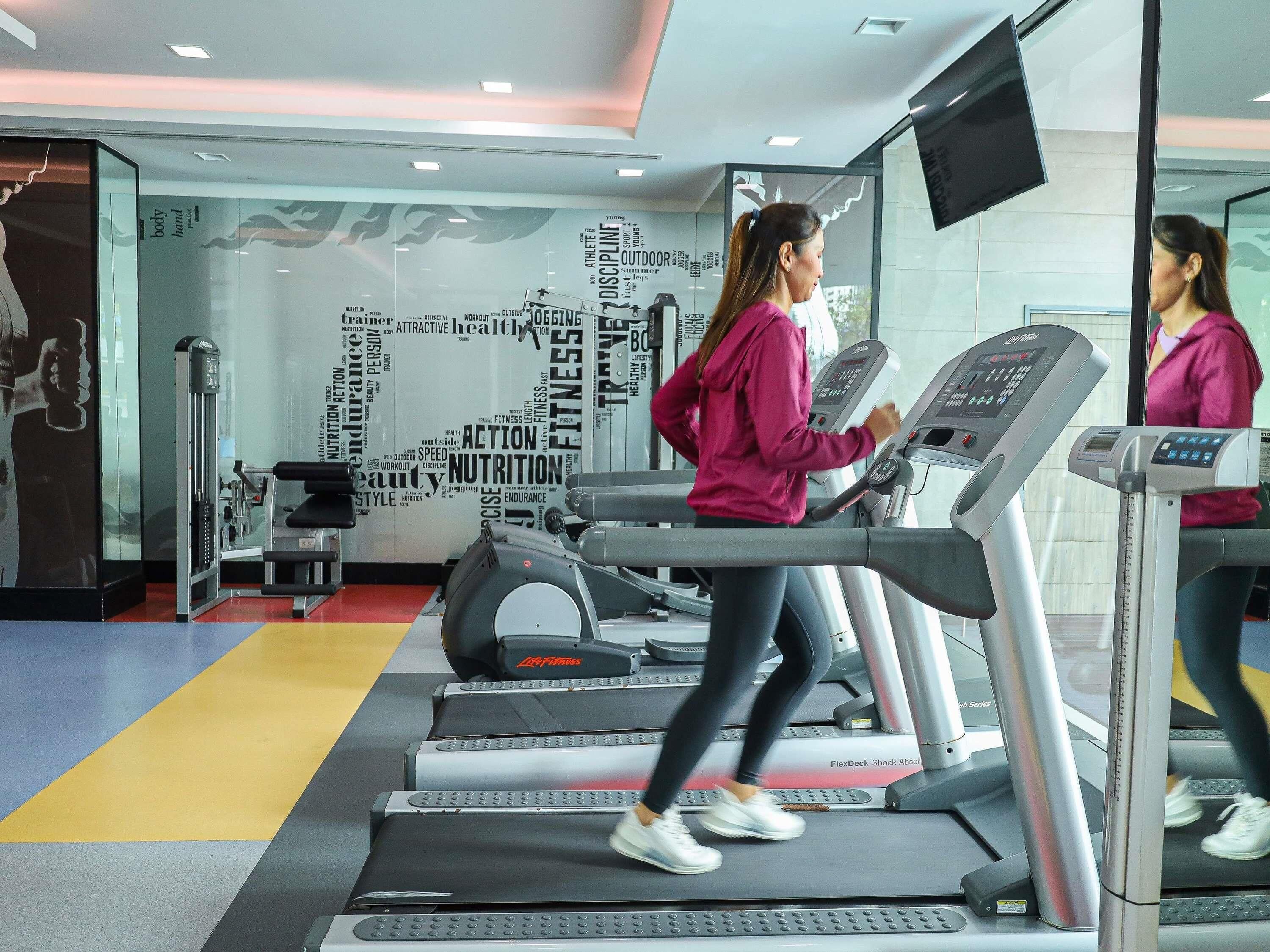 Ein Fitnessstudio mit Laufbändern, Gewichten und einer motivierenden Wand.