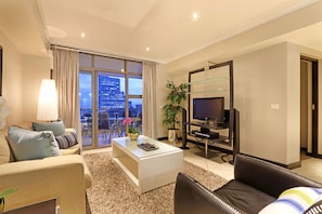 Ein modernes Wohnzimmer mit einer Couch, einem Couchtisch, einem Fernseher und einem großen Fenster mit Blick auf die Stadt.