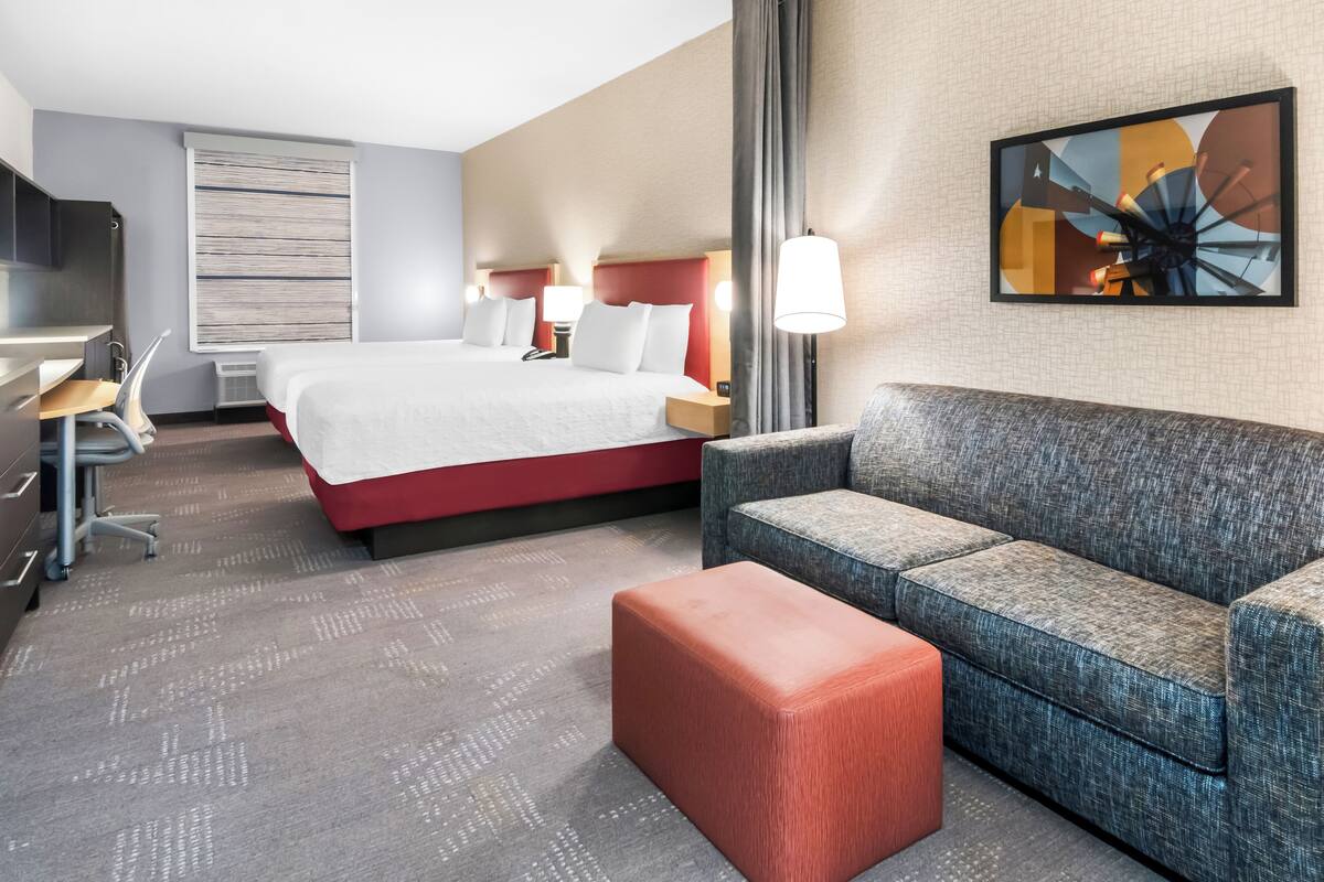 A hotel room with a bed, a sofa, a desk, and a chair.