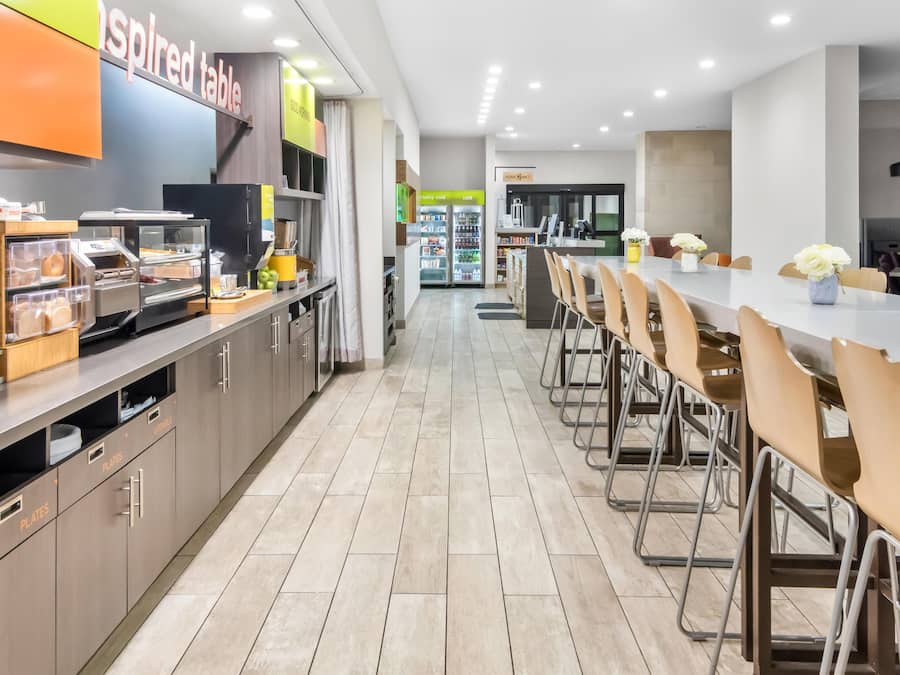 A modern cafeteria with a long counter, chairs, and a refrigerator.