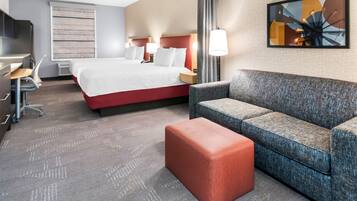 A hotel room with a bed, a sofa, a desk, and a chair.