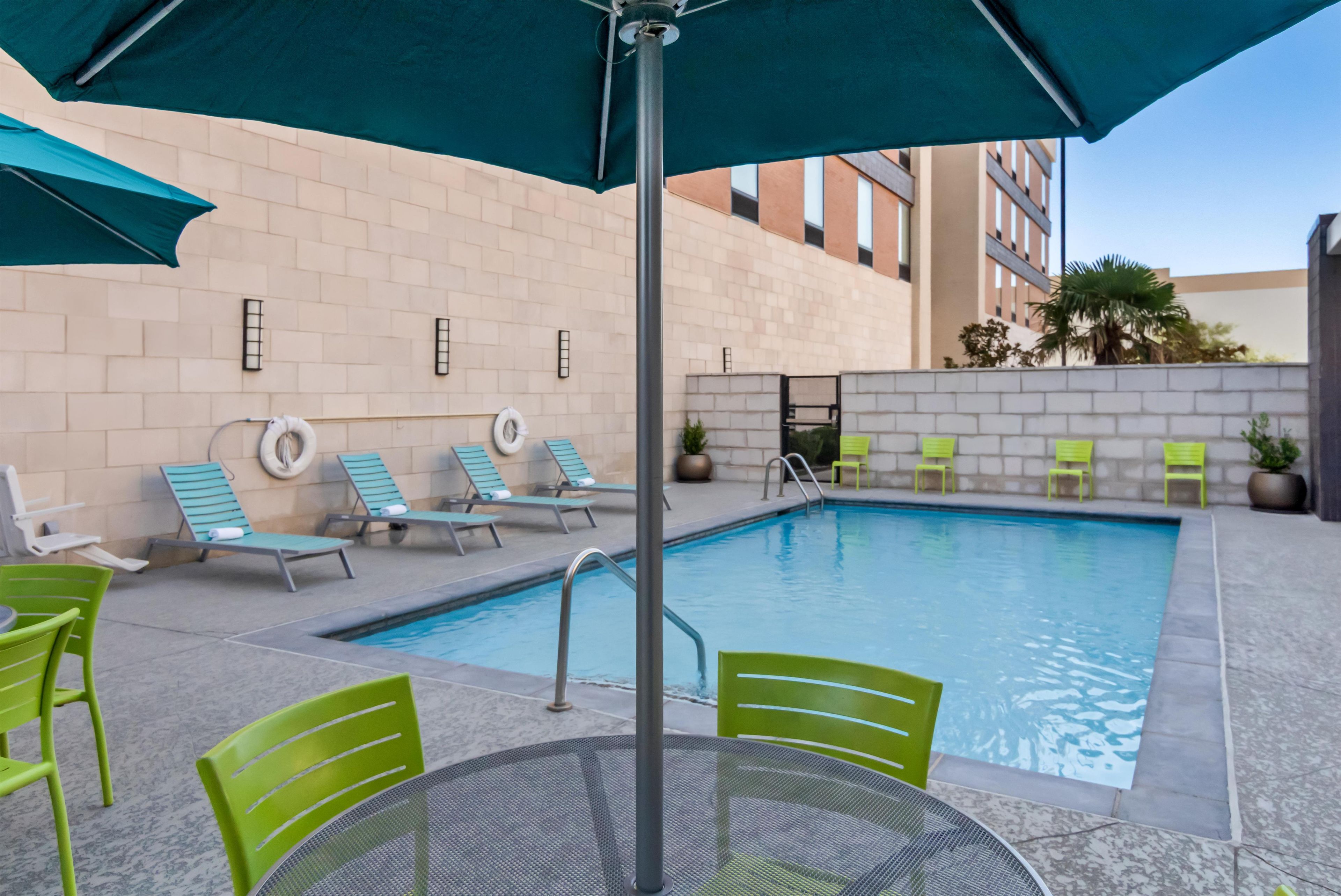 Un área de piscina con sillones reclinables y una mesa.