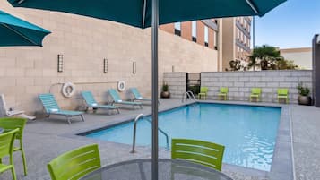 Un área de piscina con sillones reclinables y una mesa.