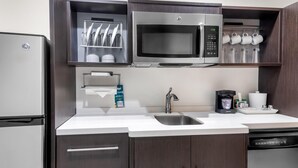 A modern kitchen with a stainless steel refrigerator, a microwave, a coffee maker, and a dishwasher. - Home2 Suites by Hilton Dallas Grand Prairie (Grand Prairie)
