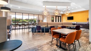 A modern dining area with a mix of seating options, including tables and booths, and a large window offering a view of the outdoors. - Home2 Suites by Hilton Dallas Grand Prairie (Grand Prairie)